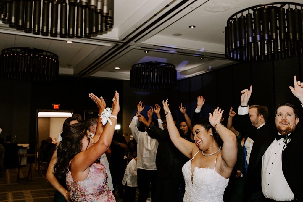 A bride and groom dance with guests of their wedding at their indoor reception at the Hyatt Regency