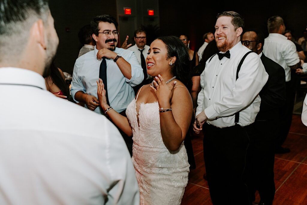 A bride and groom dance with guests of their indoor wedding reception at the Hyatt Regency
