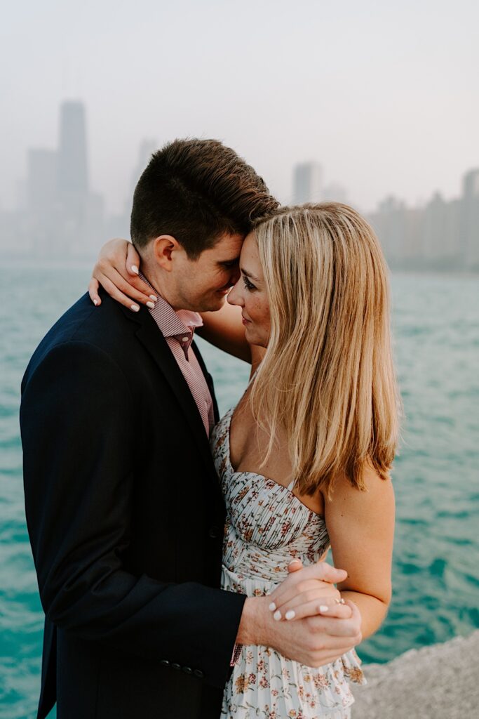 A man and woman embrace and smile while dancing in front of Lake Michigan and the Chicago skyline