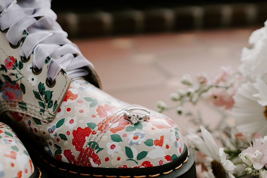 A wedding ring sits on top of a boot with a floral pattern on it