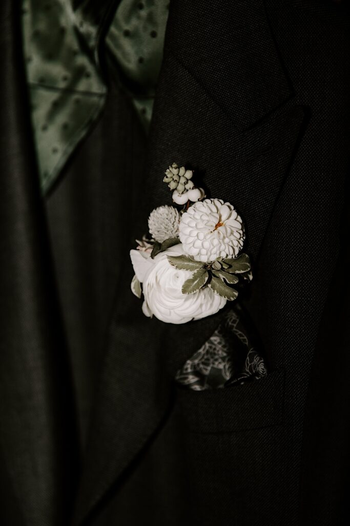 Detail photo of a white flower boutonniere on a green suit coat