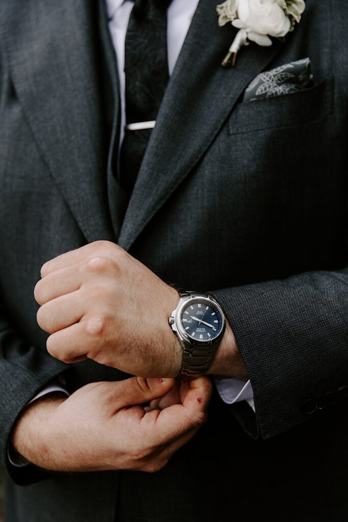 Close up photo of a groom adjusting the watch on his wrist