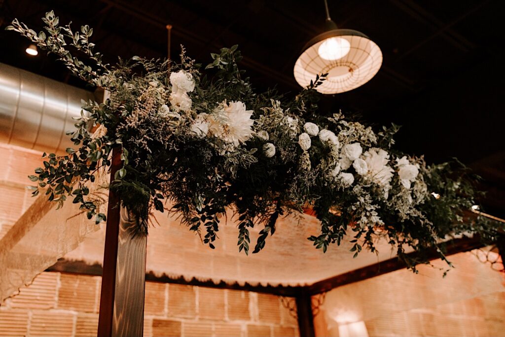 Flowers hang on an archway that is part of the ceremony space of the wedding venue The Atrium in Milwaukee