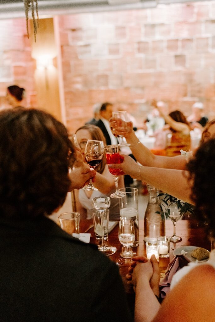 Guests of a wedding reception raise their glasses together to toast during a speech