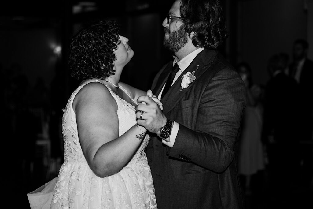 Black and white photo of a bride and groom sharing their first dance during their indoor wedding reception at The Atrium in Milwaukee
