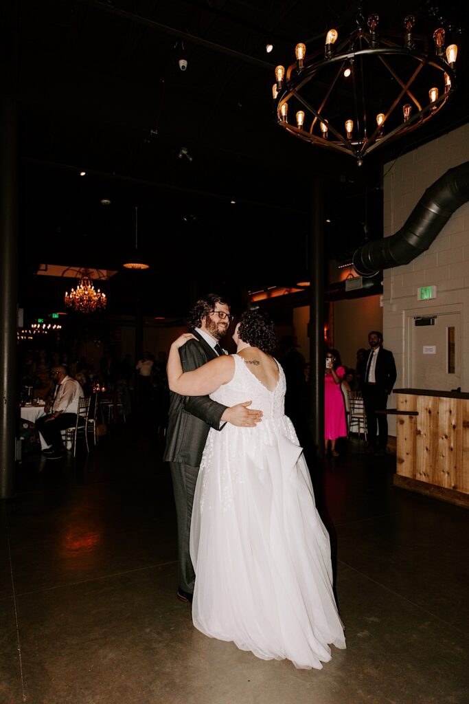A bride and groom dance together during their indoor wedding reception