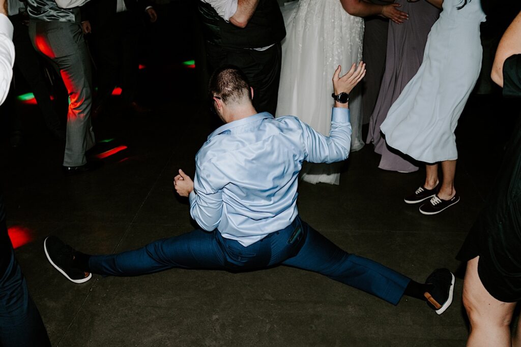 A member of a wedding reception at The Atrium in Milwaukee does the splits while in the middle of a dance circle