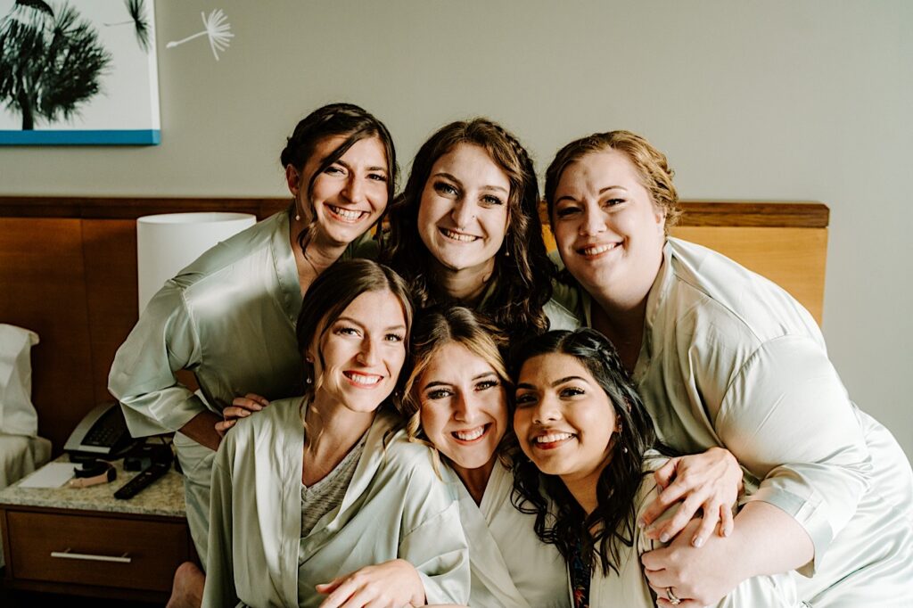 A bride and her 5 bridesmaids all smile at the camera before getting ready for the bride's Chicagoland wedding day