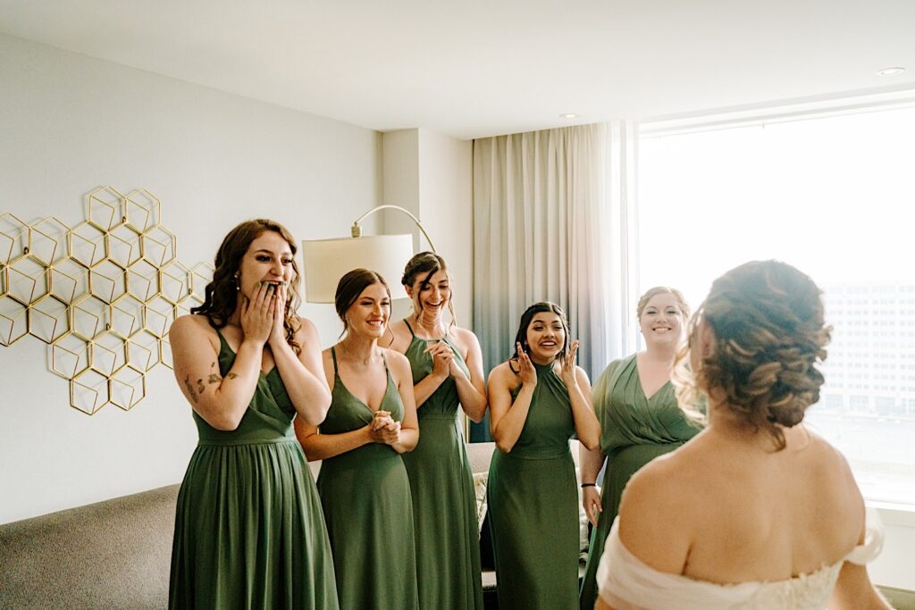 5 bridesmaids react as they see the bride in her wedding dress for the first time after getting ready for her Chicagoland wedding day
