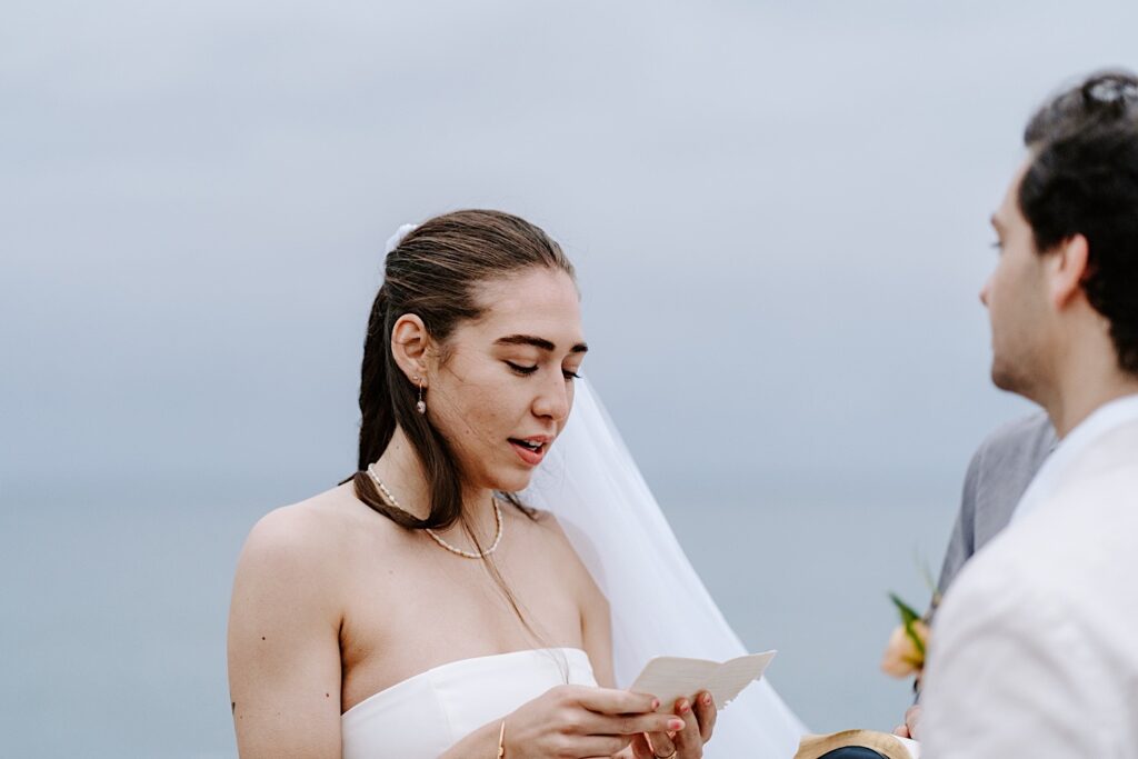 During a destination elopement ceremony in San Diego a bride reads her vows to the groom while he stands in front of her