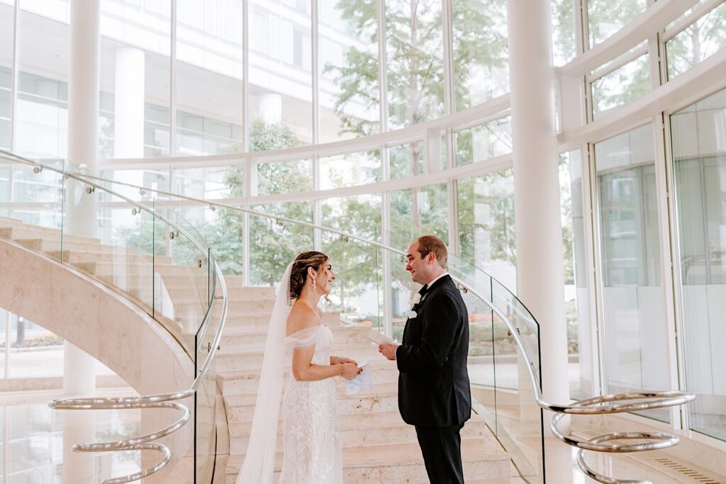 A bride and groom read their private vows to one another during their first look in the lobby of their hotel 
