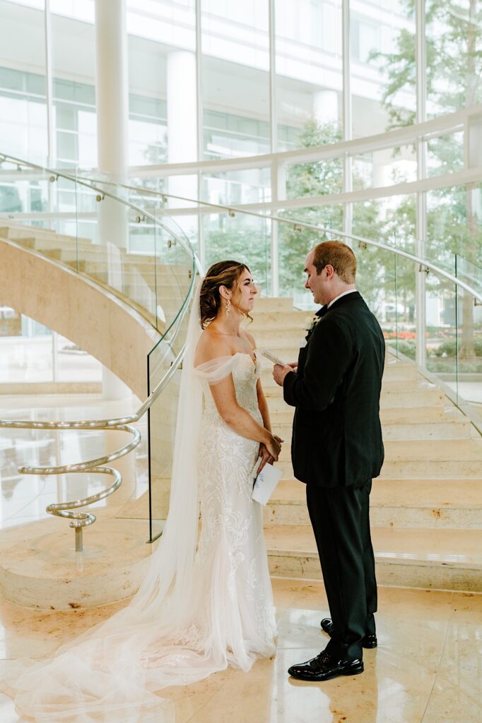 A groom reads his vows to the bride after their first look in the lobby of their hotel