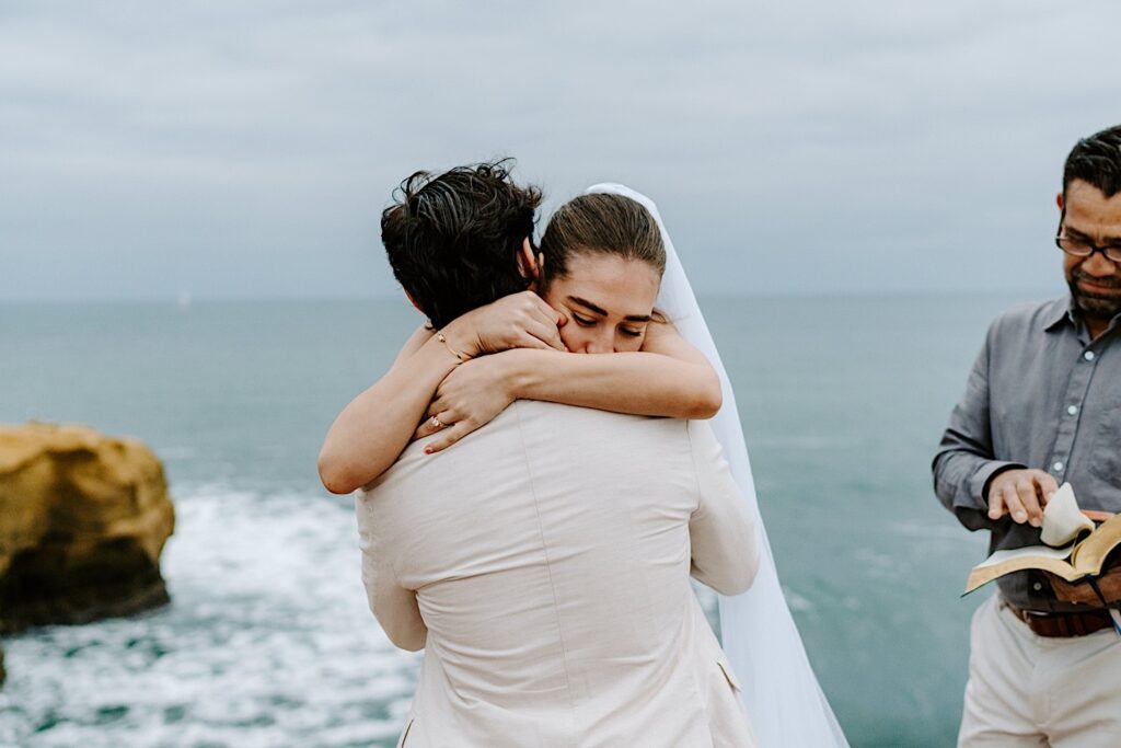 A bride and groom hug one another after the ceremony of their destination elopement to the cliffs of San Diego
