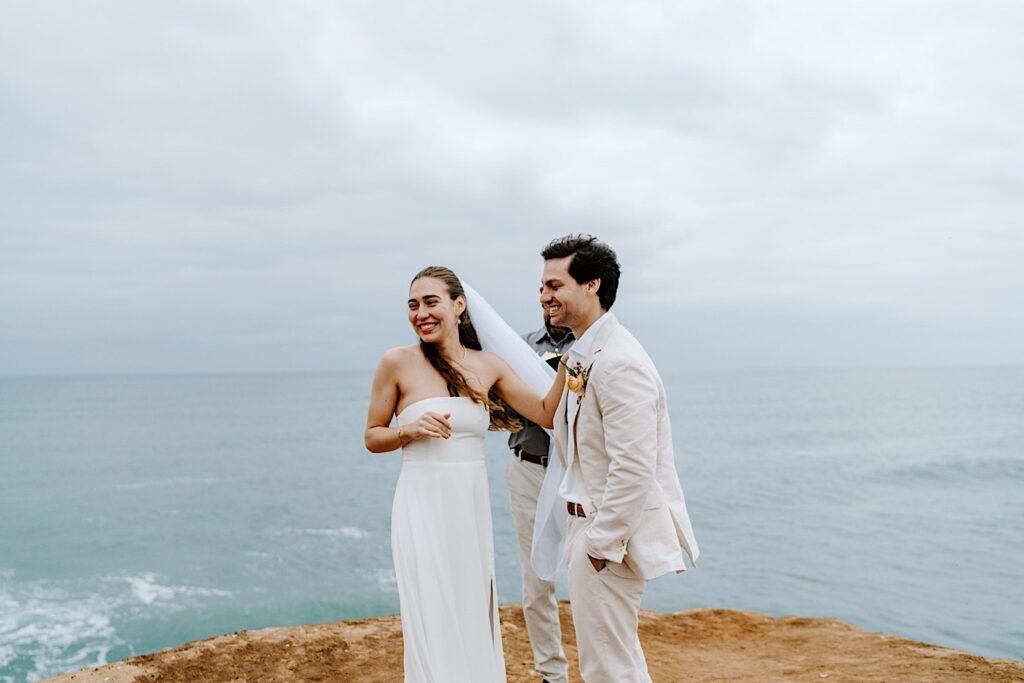 A bride and groom smile while turning to the guests of their elopement ceremony at the cliffs of San Diego