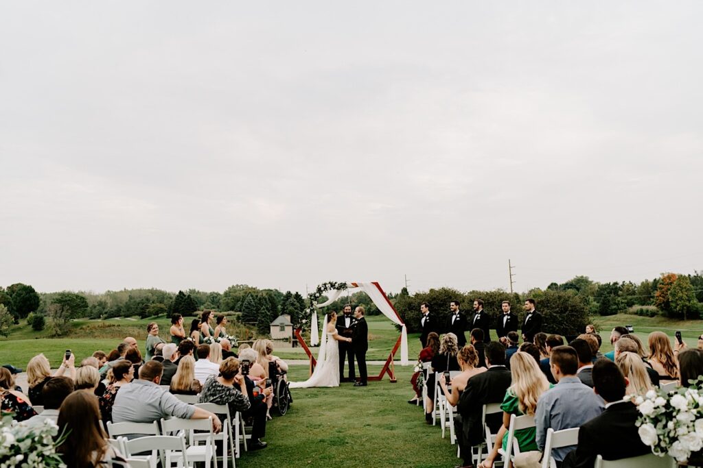 An outdoor wedding ceremony at the Makray Golf Club in the Chicagoland area takes place on a cloudy day