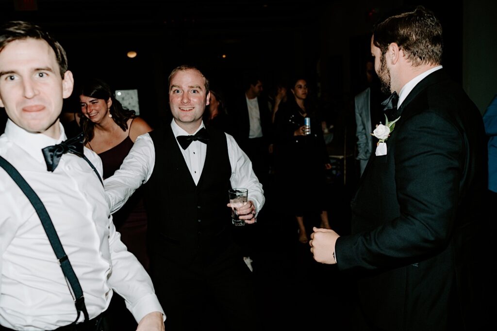 A groom smiles at the camera while dancing with some of his groomsmen during an indoor wedding reception at the Makray Golf Club in the Chicagoland area