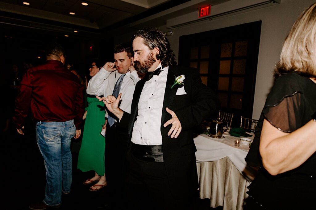 A groomsman dances with other guests during an indoor wedding reception at the Makray Golf Club in the Chicagoland area