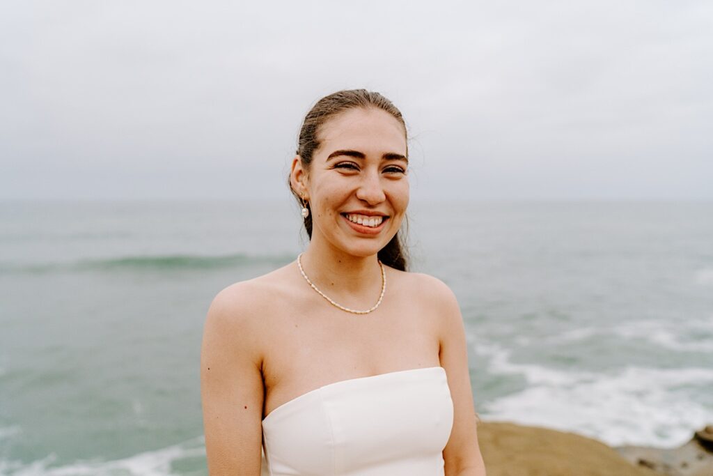 Portrait photo of a bride smiling at the camera while at the cliffs in San Diego for her destination elopement