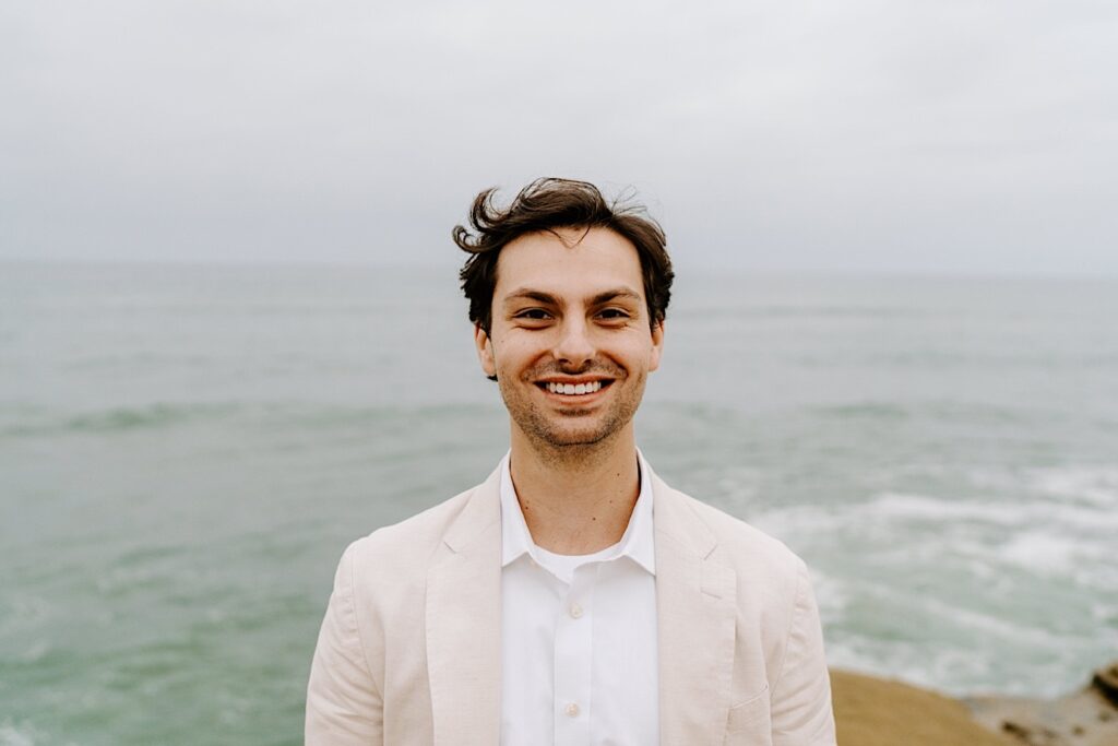 Portrait photo of a groom smiling at the camera while at the cliffs in San Diego for his destination elopement