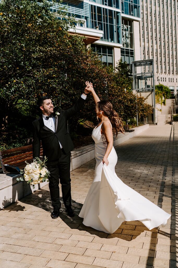 A bride and groom dance together while standing on the Chicago Riverwalk outside the Voco Hotel
