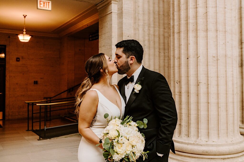 A bride and groom kiss one another while inside of Chicago's Union Station