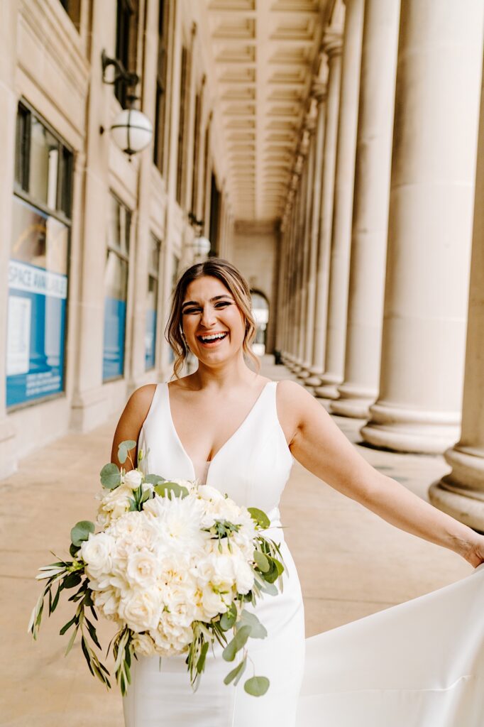 A bride smiles as she walks towards the camera while playing with her dress outside of Chicago's Union Station