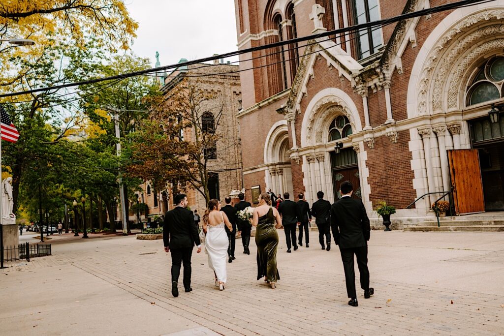 A bride and groom walk with their wedding parties towards St Michael Church in Chicago for the wedding ceremony