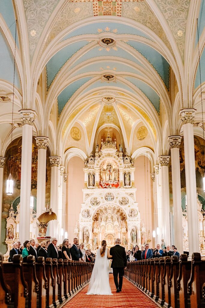 A bride and her father walk down the aisle of St Michael Church in Chicago during the bride's wedding ceremony