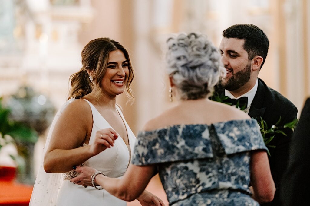 A bride smiles as the mother of the groom congratulates her after the two's wedding ceremony inside of St Michael Church in Chicago