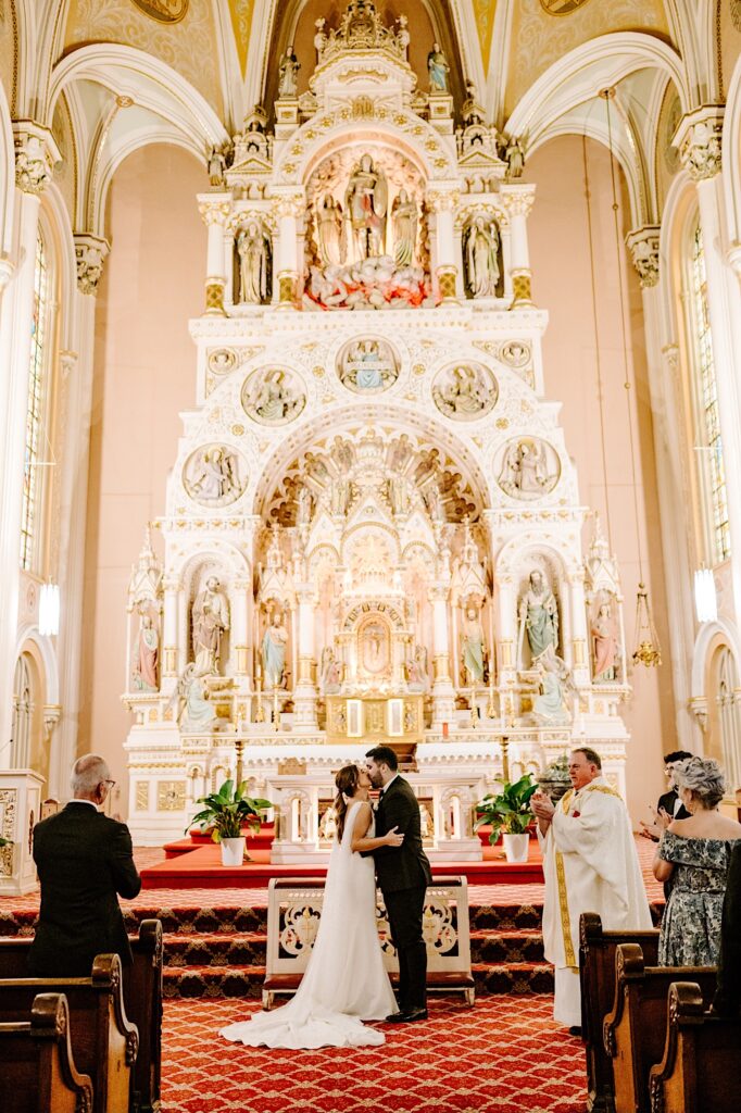 A bride and groom kiss one another during their wedding ceremony inside of St Michael Church in Chicago