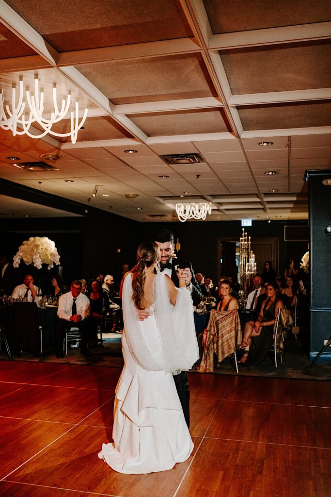 A bride and groom share their first dance together as guests watch during their reception inside the Voco Hotel in Chicago