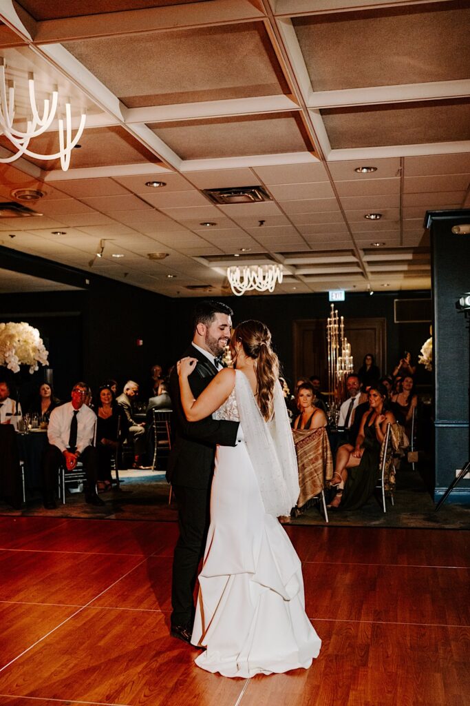 A bride and groom smile at one another while dancing during their reception inside the Voco Hotel in Chicago