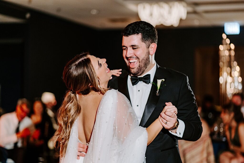 A bride and groom laugh while sharing their first dance together during their wedding reception at the Voco Hotel in Chicago