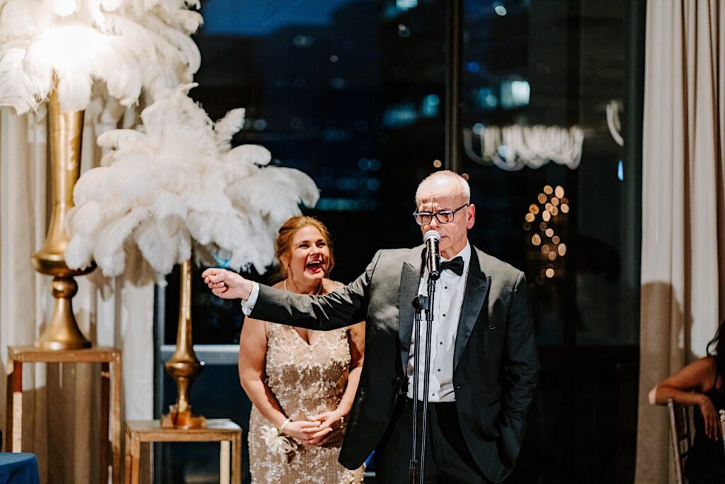 The father of the bride gives a speech into the microphone during a wedding reception inside of the Voco Hotel in Chicago