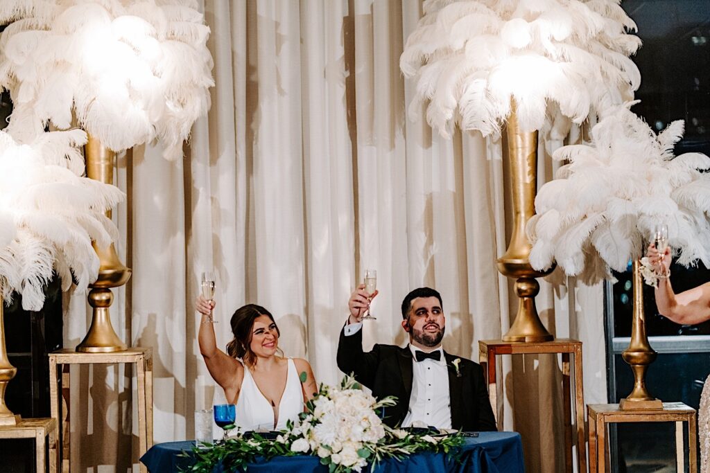 A bride and groom raise their glasses during a speech for their wedding reception inside of the Voco Hotel in Chicago