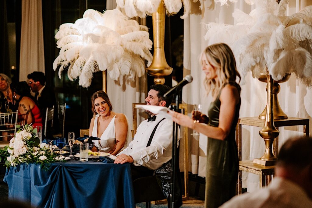 A bride and groom laugh while listening to one of the bridesmaids give a speech during their reception at the Voco Hotel in Chicago