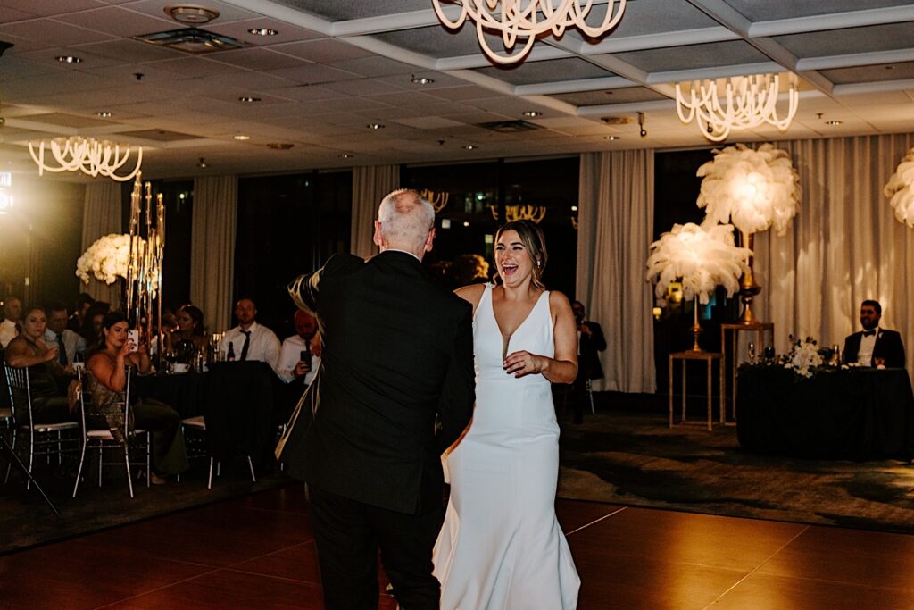 A bride smiles while dancing with her father as guests watch during her wedding reception at the Voco Hotel in Chicago