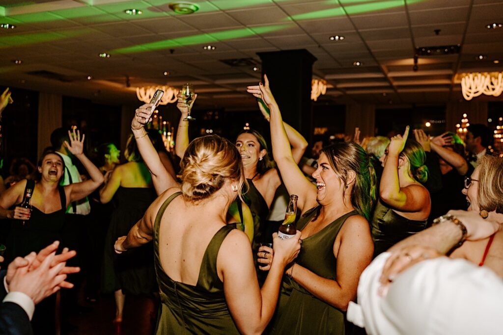 Bridesmaids dance together while surrounded by other guests during a wedding reception at the Voco Hotel in Chicago