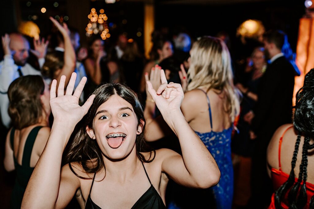 A young girl makes a funny face at the camera while dancing with other guests during an indoor wedding reception at the Voco Hotel in Chicago