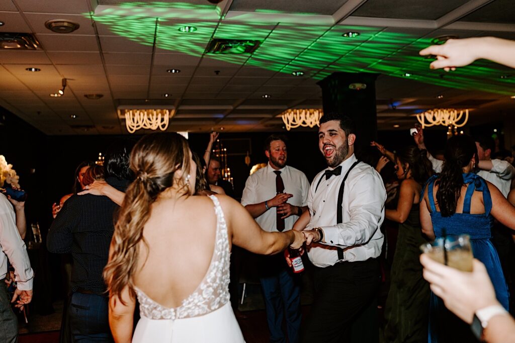 A groom smiles at the bride while they dance alongside their friends during their wedding reception at the Voco Hotel in Chicago