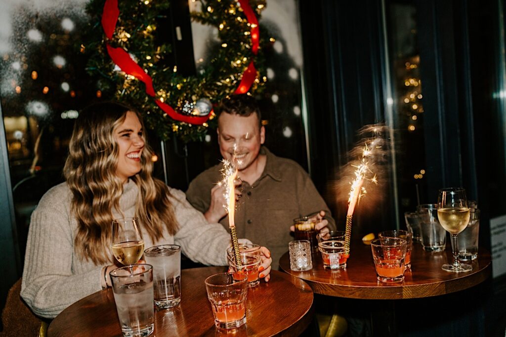 A couple sit in The Bandit of Chicago and have drinks with sparklers given to them as they celebrate their proposal in Chicago's West Loop