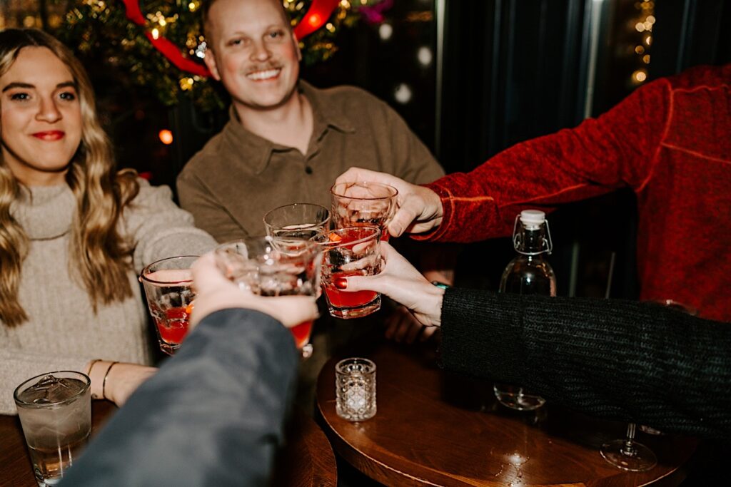 A couple sit at a table inside The Bandit and raise their glasses with their friends to celebrate their proposal in Chicago's West Loop