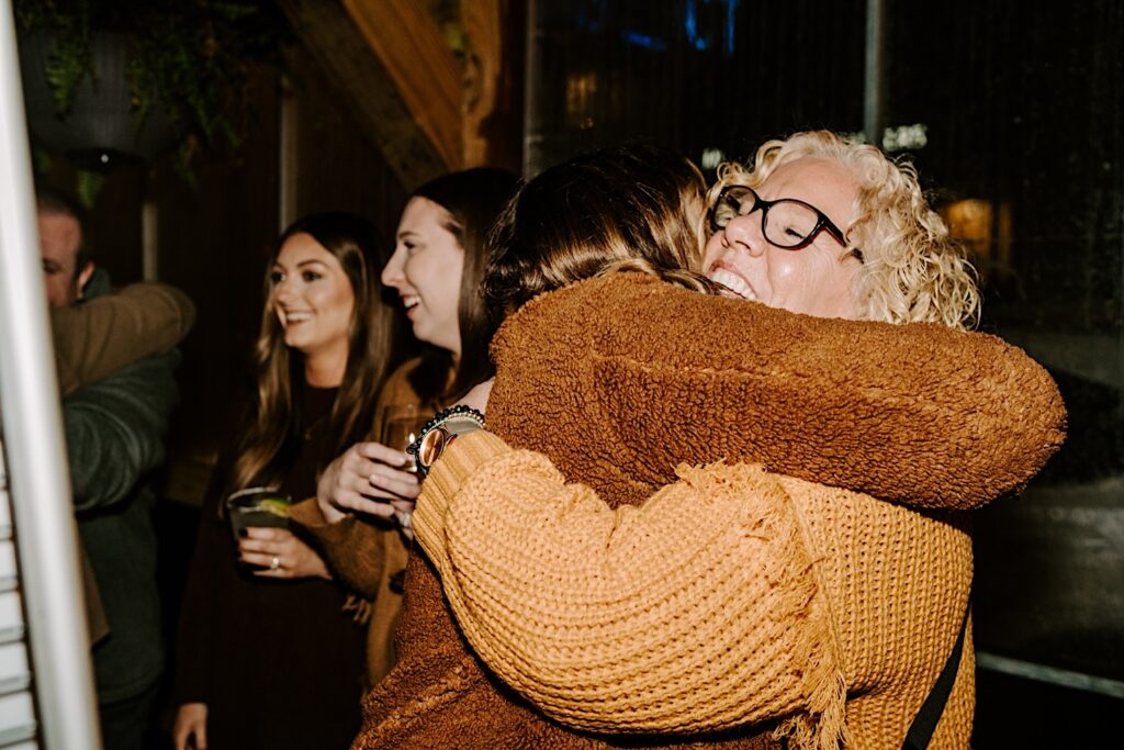 A woman is hugged by her mother while inside a bar after she was proposed to in Chicago's West Loop 