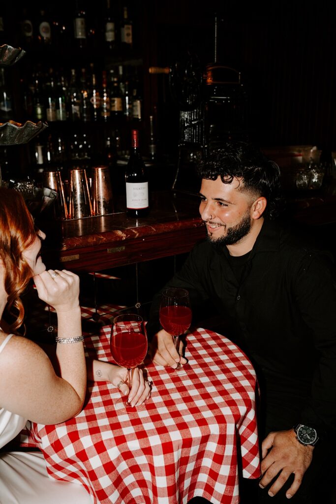 A man smiles at a woman sitting across the table from him while in a Chicago bar