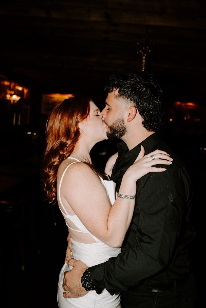 A couple kiss one another as they embrace while in a Chicago bar