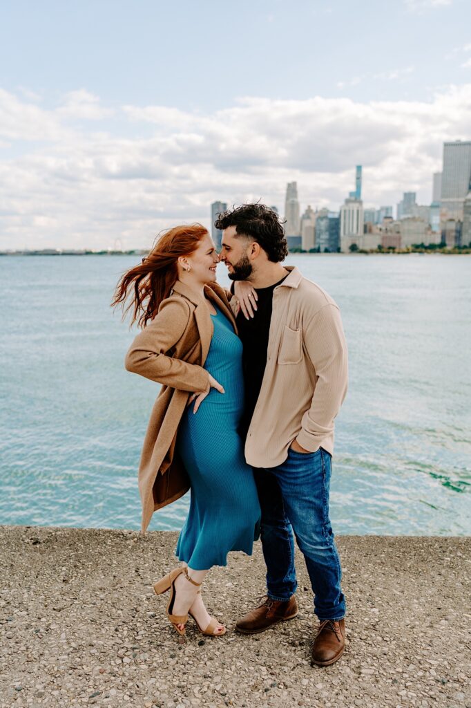 A couple smile at one another while touching their noses together while standing in front of Lake Michigan and the Chicago skyline
