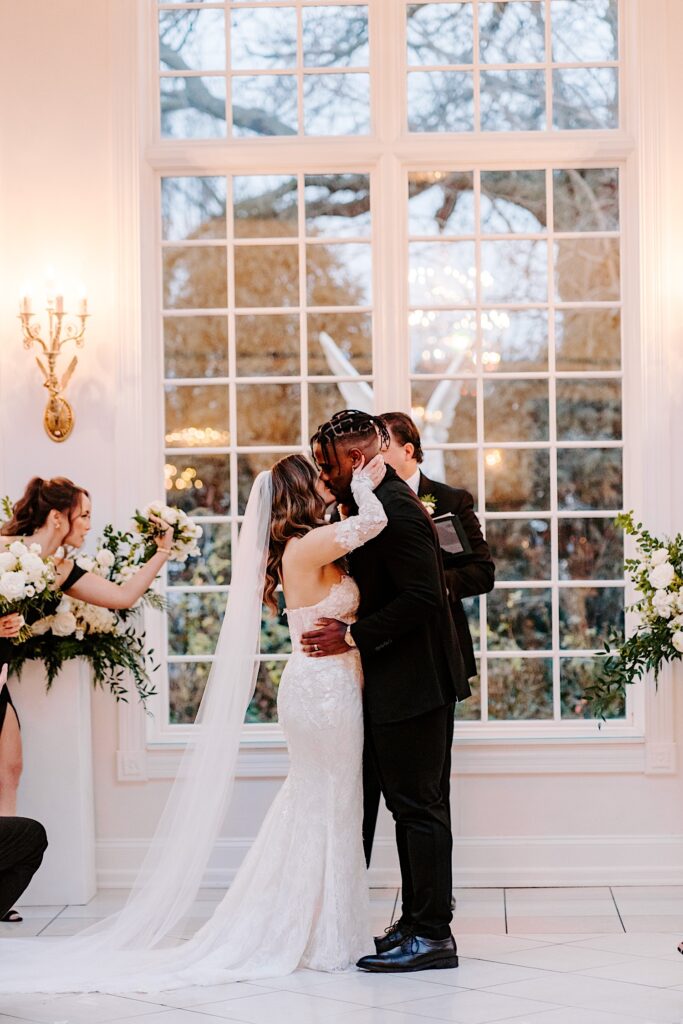 A bride and groom kiss one another after their ceremony inside The Haley Mansion