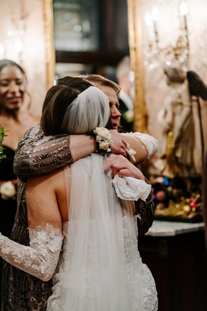 A bride and her mother hug one another after the bride's wedding ceremony