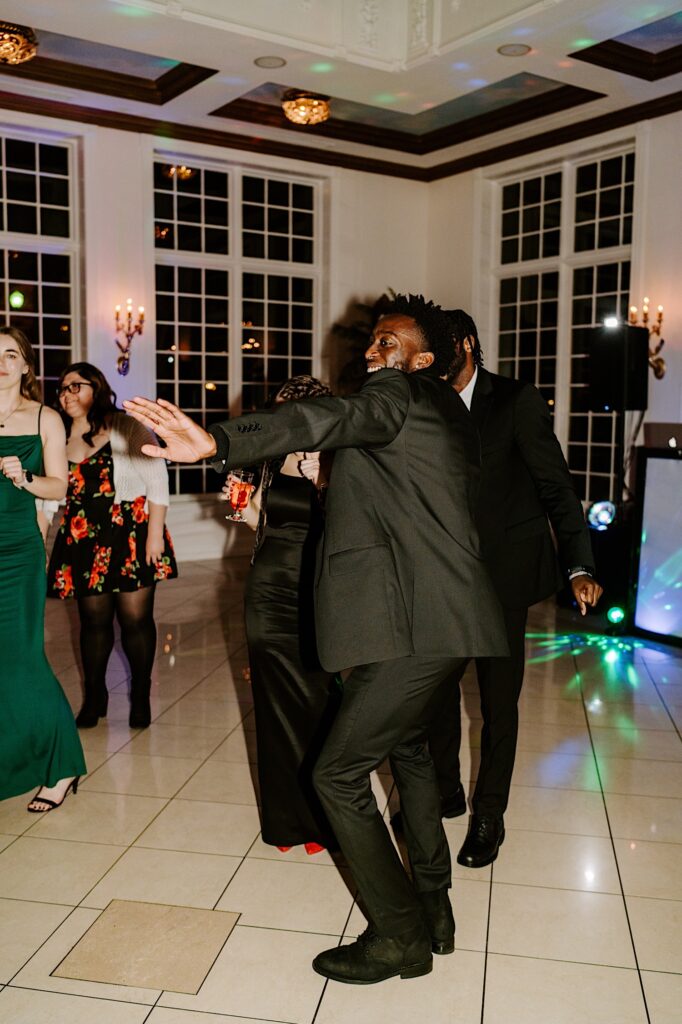 Groomsmen dance together on the dance floor during an indoor wedding reception