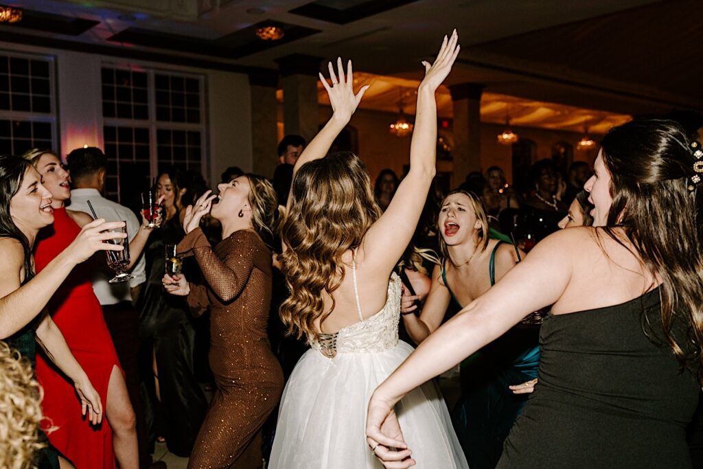 A bride dances with her friends on the dancefloor during an indoor wedding reception at The Haley Mansion